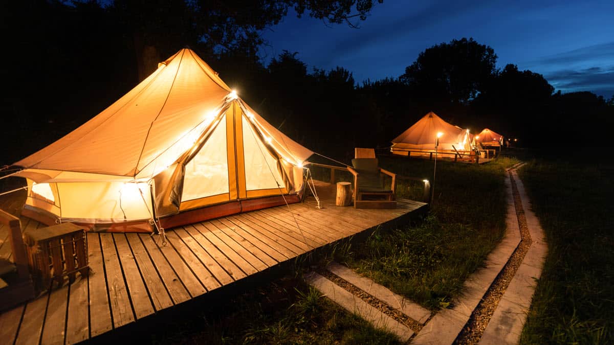 glamping yurt with wooden sidewalks and decorative lights on yurt